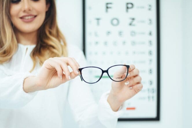 woman holding glasses eye testing
